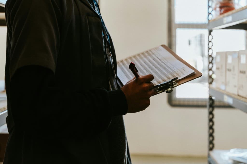 Merchant counting inventory on a clipboard in the warehouse