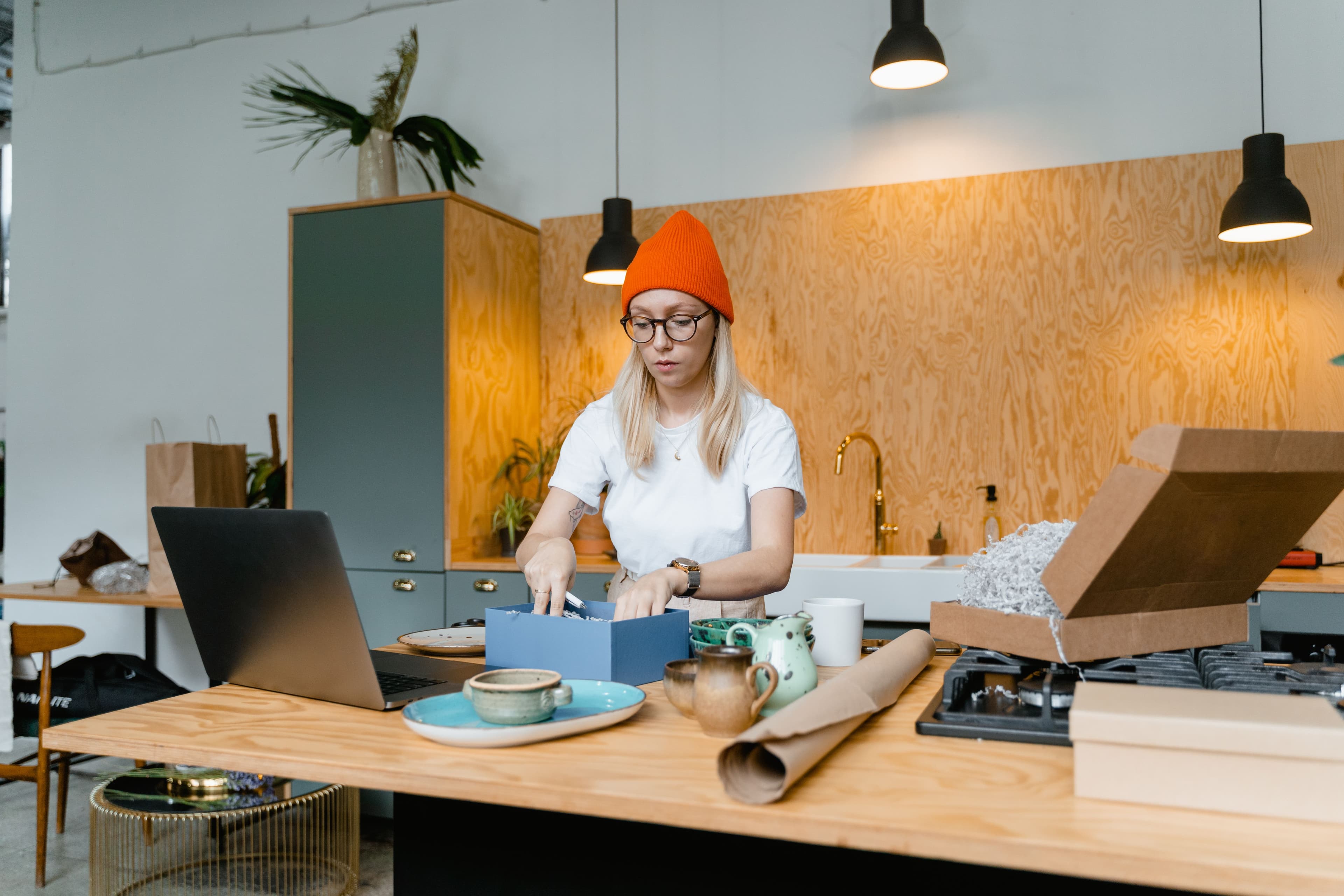 Entrepreneur packing orders at her workshop with a laptop